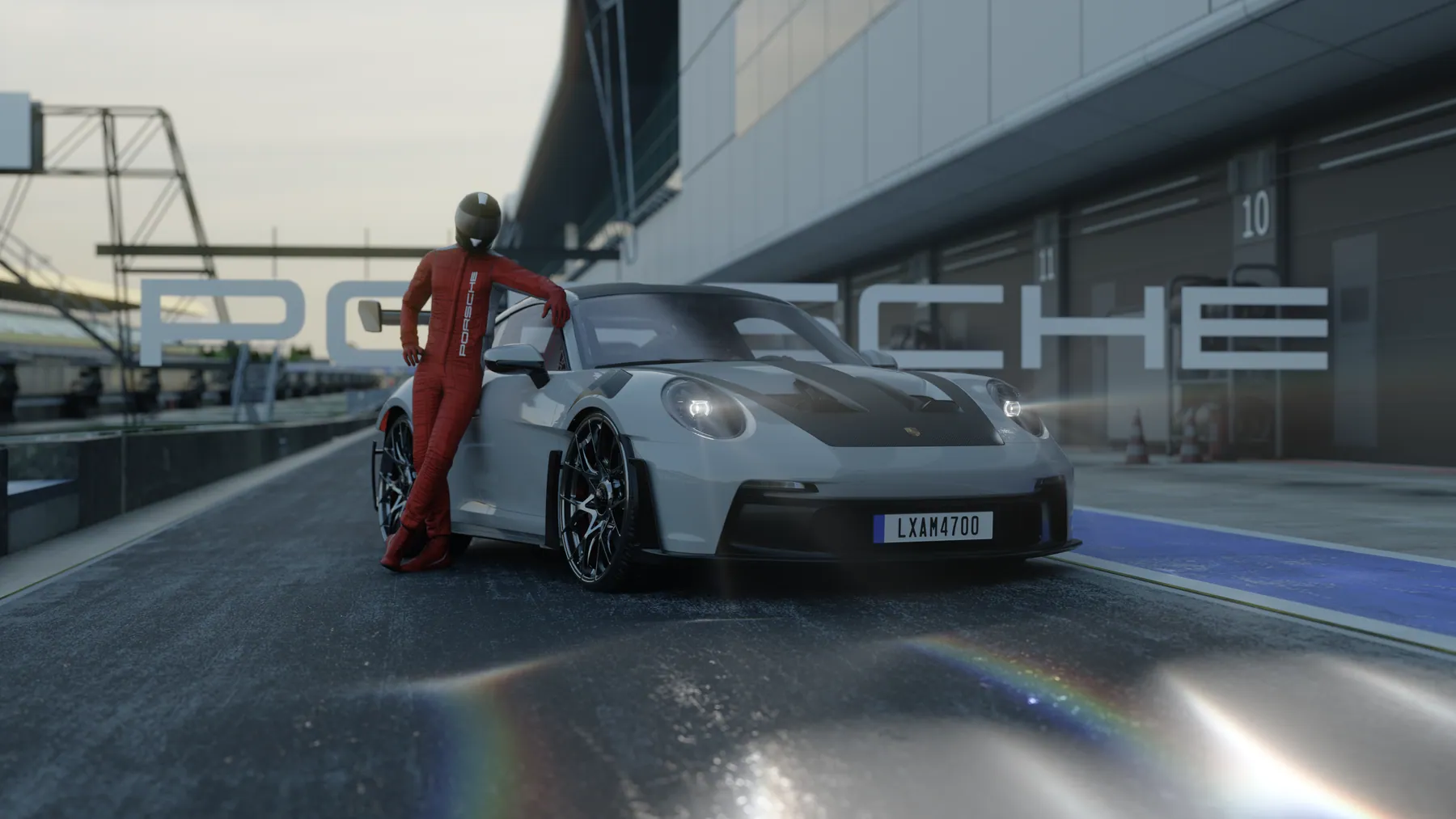 Tay đua mặc đồ đỏ đứng tựa vào Porsche 911 trong pit lane