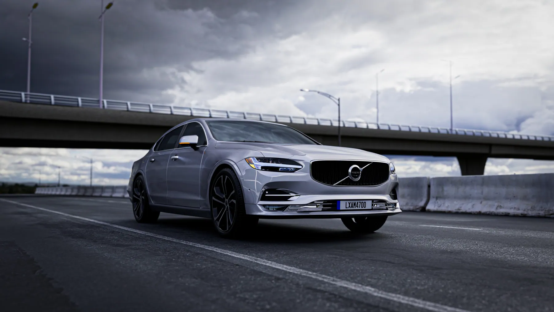 Volvo S90 chạy trong phố lúc chiều tối, đèn pha bật sáng